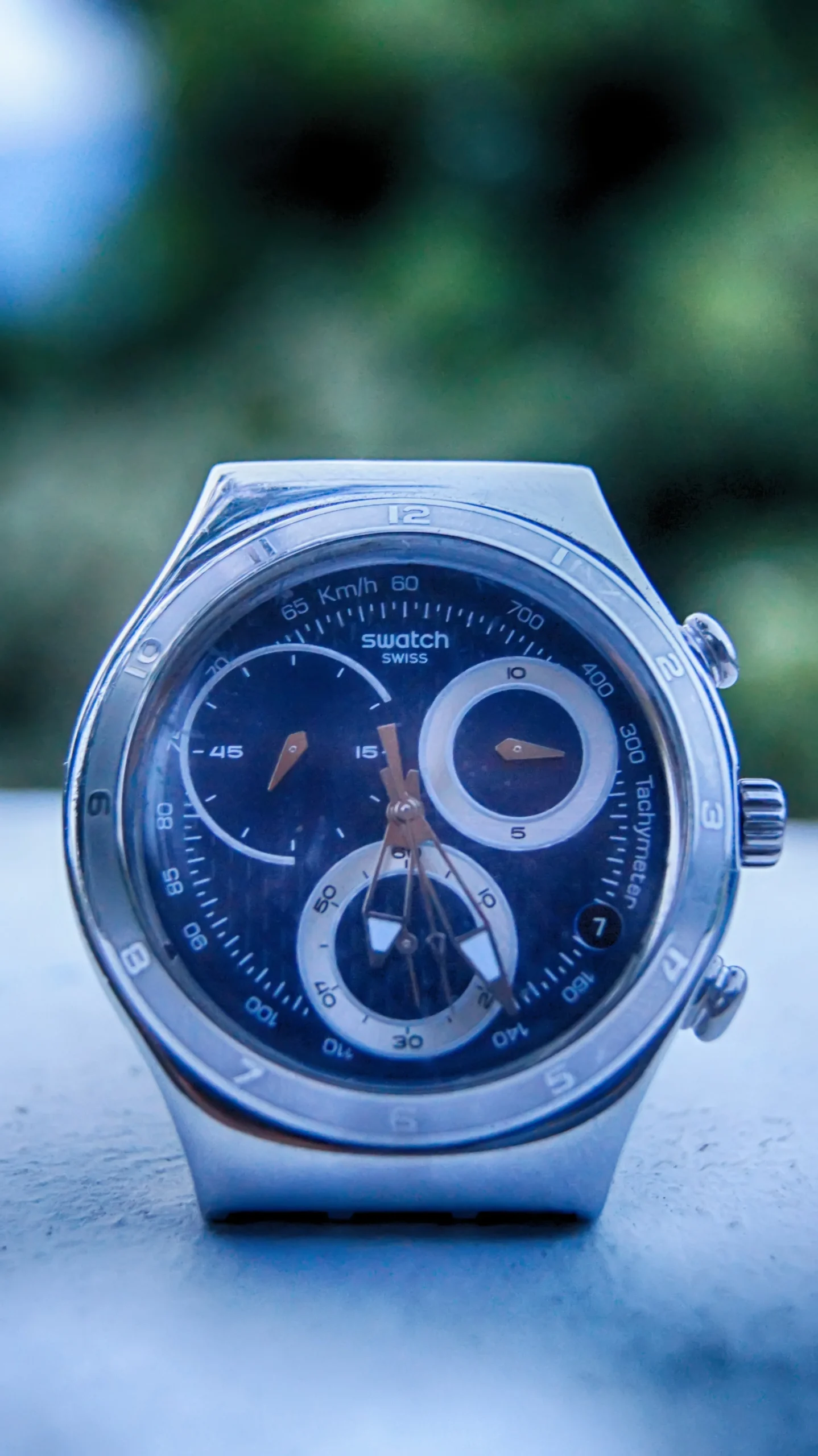 Close-up of a wristwatch dial and chronograph pushers, illustrative image related to Swatch-style chronograph design